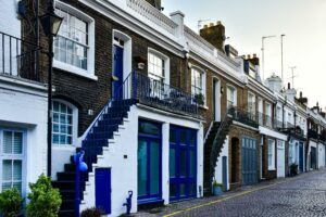 Street view of traditional brick terraced houses with blue doors and railings, representing a typical residential neighborhood in the UK.